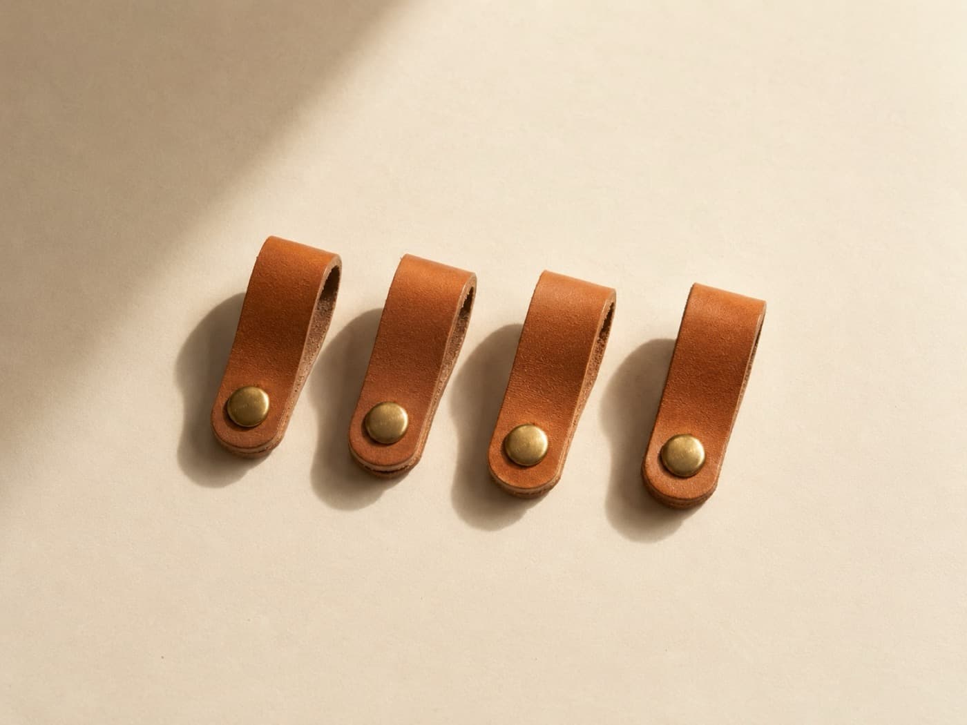 Cable Catch Set of 4 — Four snapped straps that keep a loose cord from sliding off the desk edge. Passive leather only.