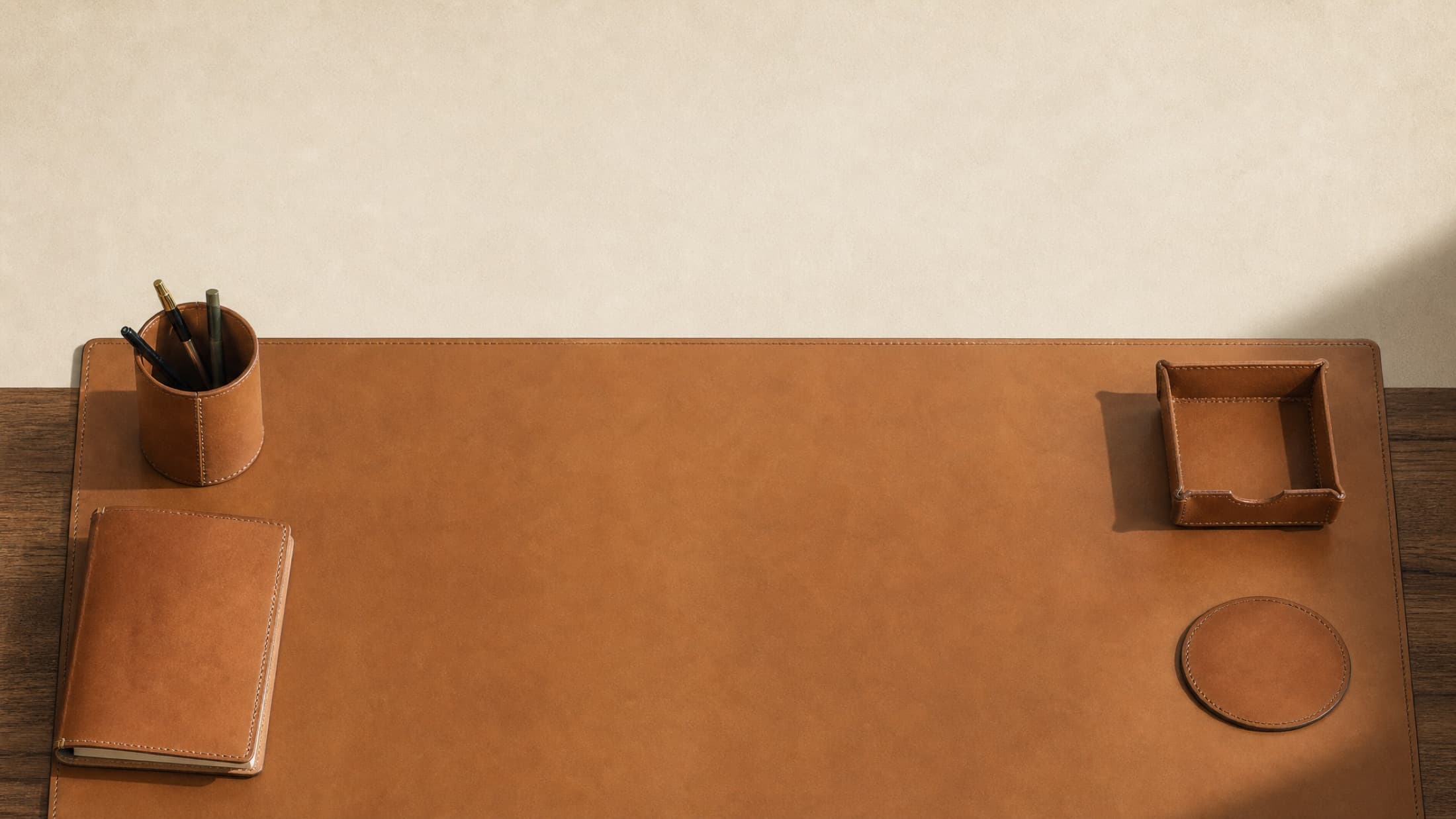 A writing desk dressed in flat leather, photographed from directly above as a magazine spread