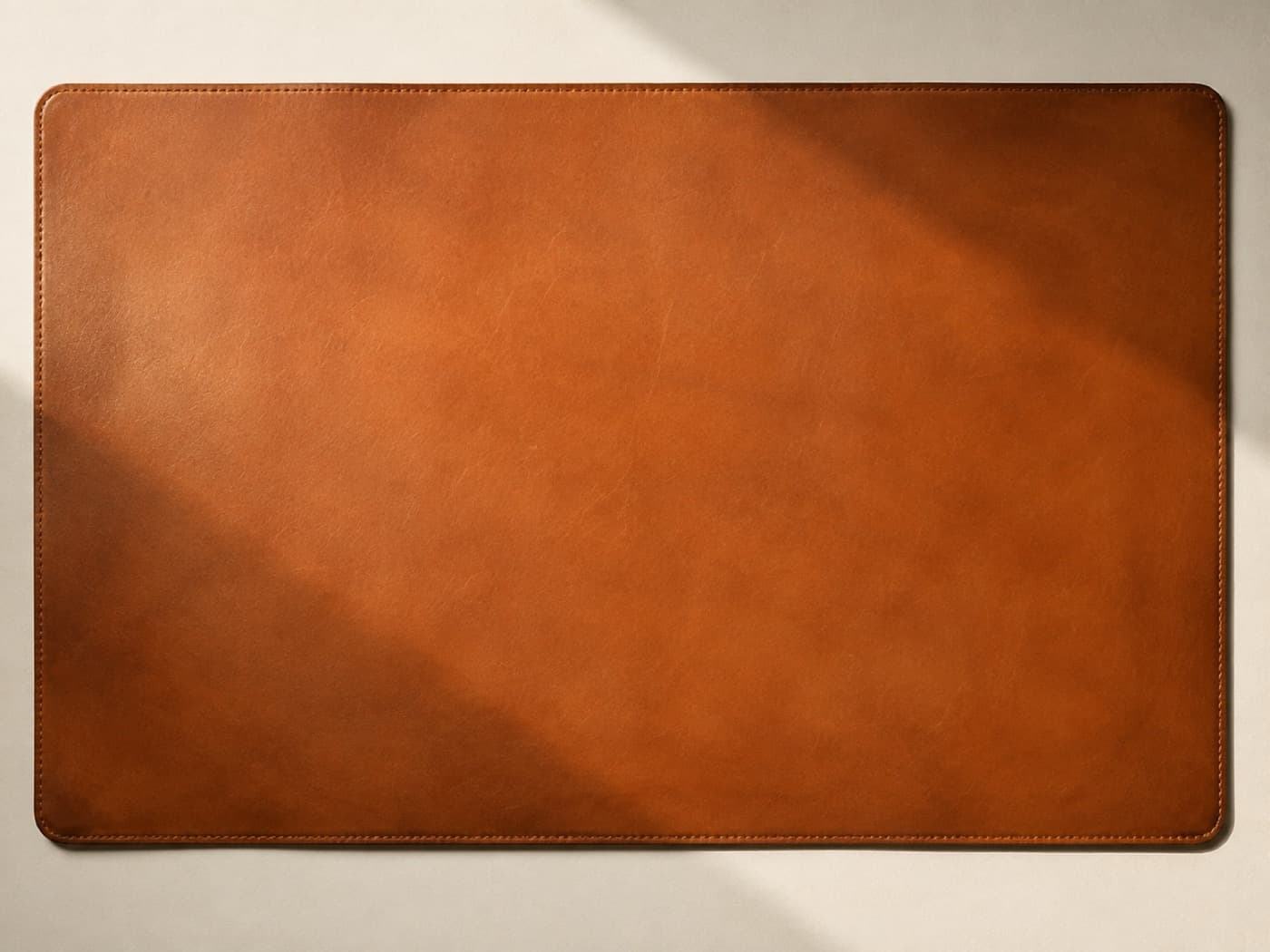 A large tan leather desk mat photographed from directly above on cream paper