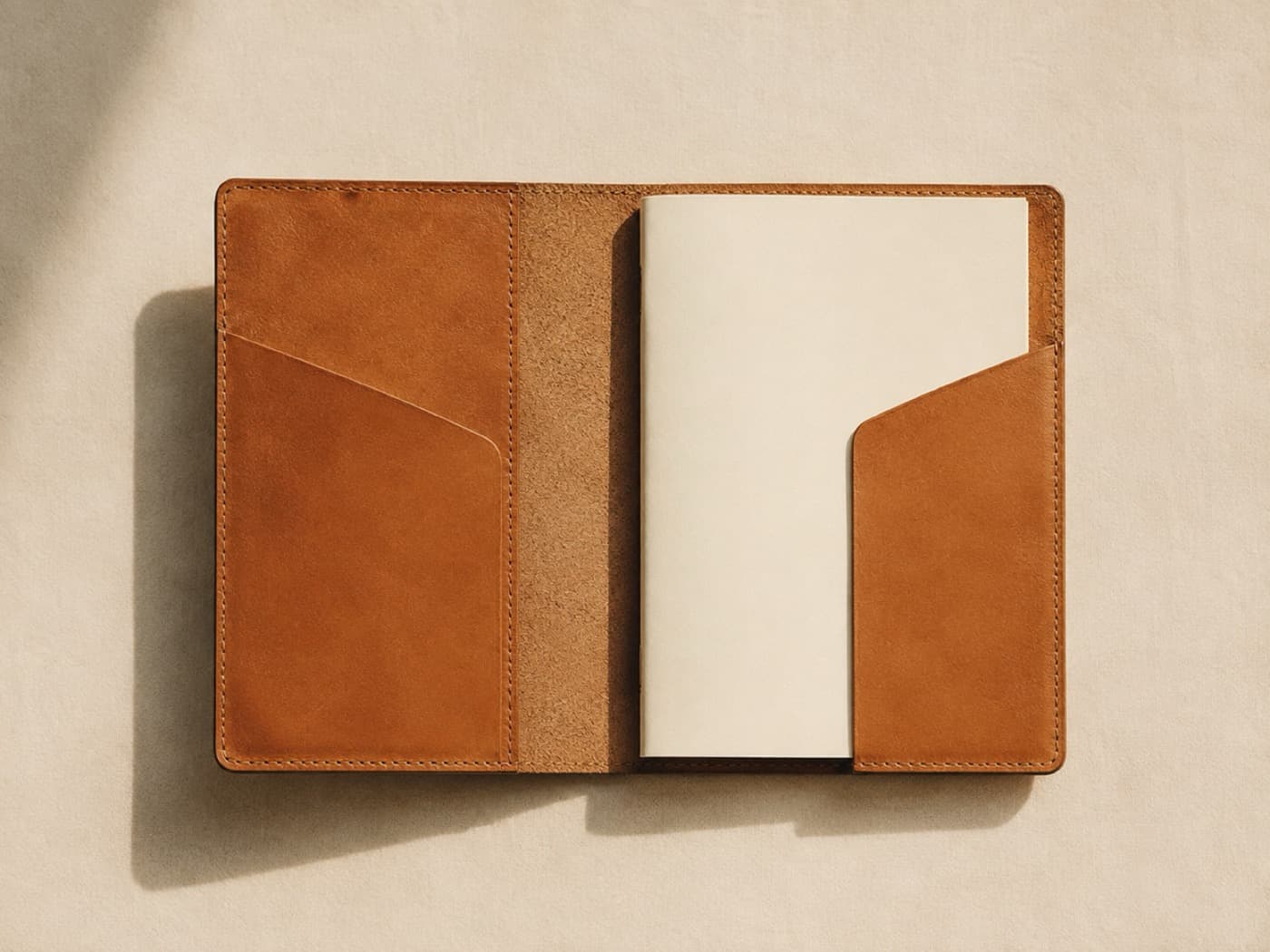 A large leather notebook cover lying open flat, showing two inner slip pockets