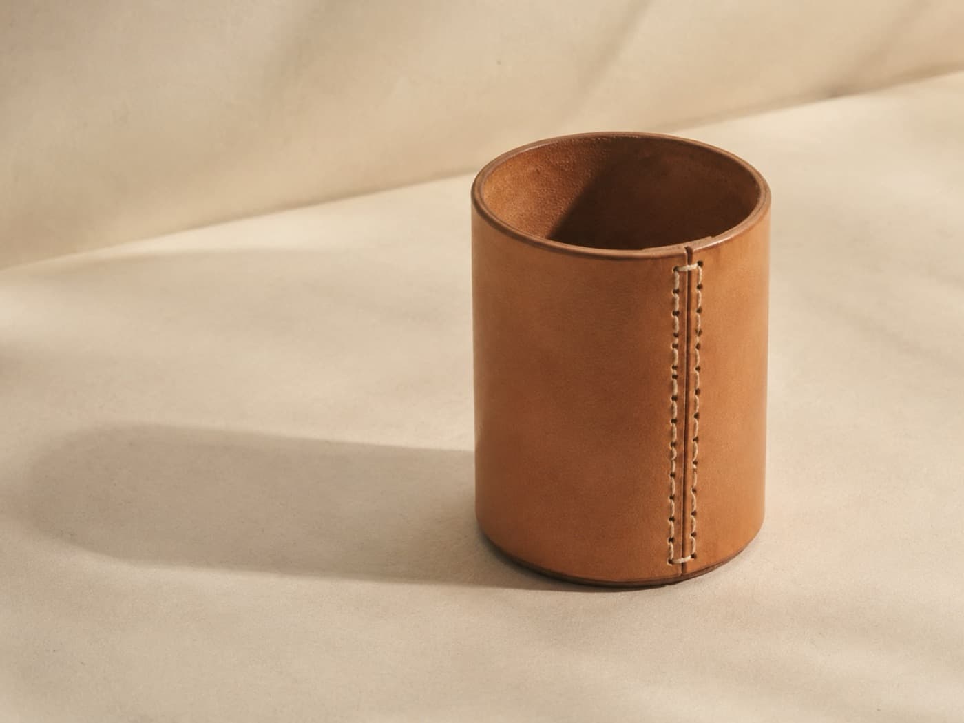 A cylindrical leather pen cup with a single saddle-stitched seam